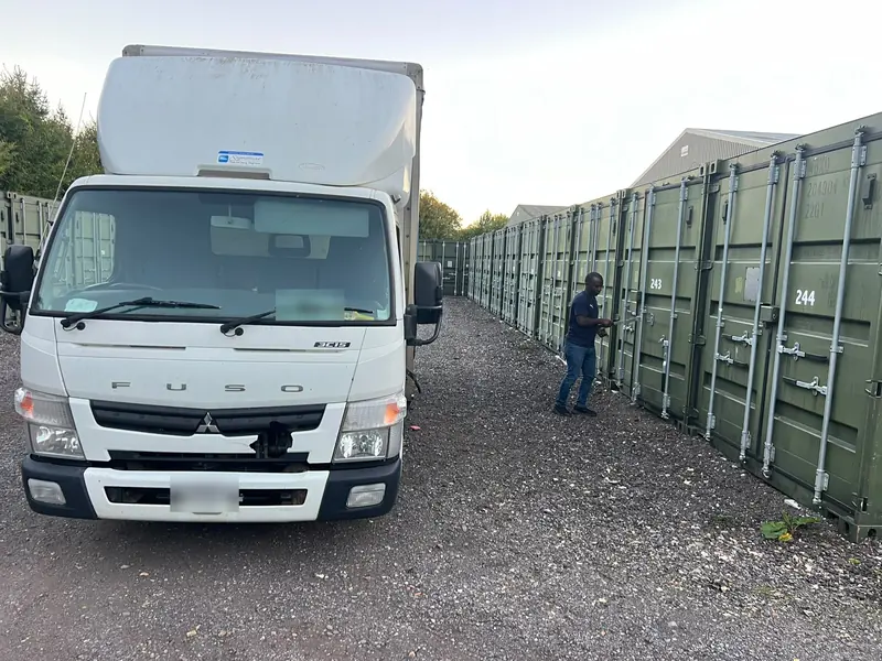 Our removal truck parked beside a row of green storage containers while one is opened