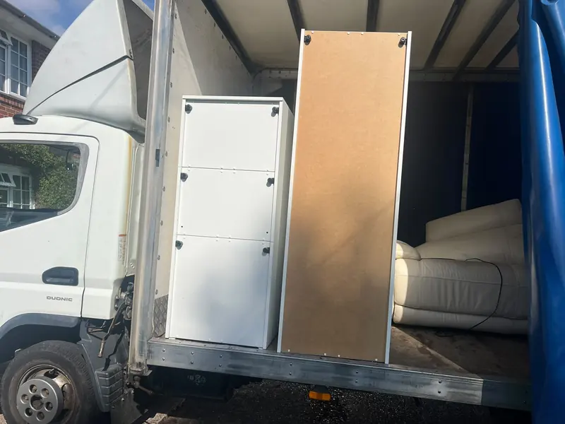 Our removal truck with its side curtain open, loaded with white wardrobe units and a cream leather sofa