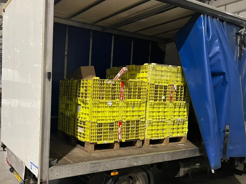 Our curtain-side truck inside a warehouse, loaded with two pallets of yellow crates